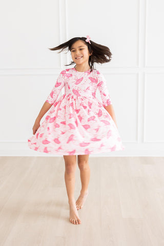 Young girl wearing a pink ballerina dress against a white background