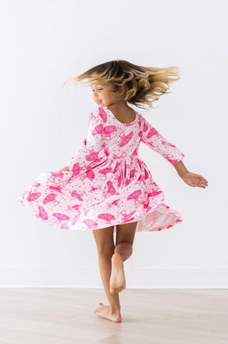 Child wearing a pink ballerina dress dancing on a white background