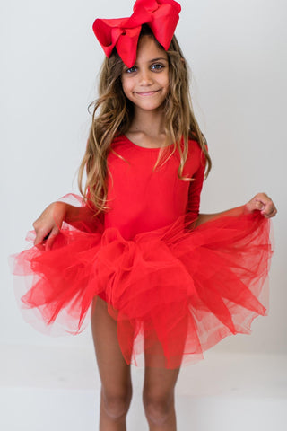 Young girl wearing a red dress with a large red bow on a white background