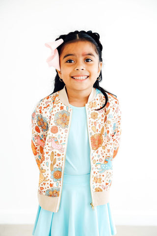 Young girl wearing a floral cardigan over a light blue dress on a white background