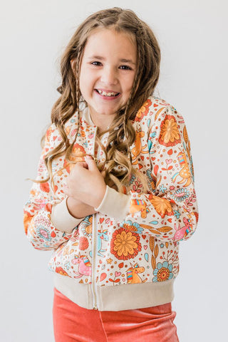 Young girl wearing a colorful floral jacket against a plain background