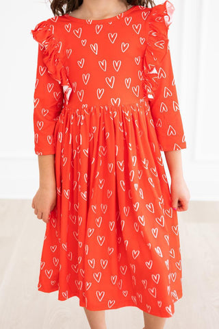 Red dress with white heart patterns worn by a person on a light background