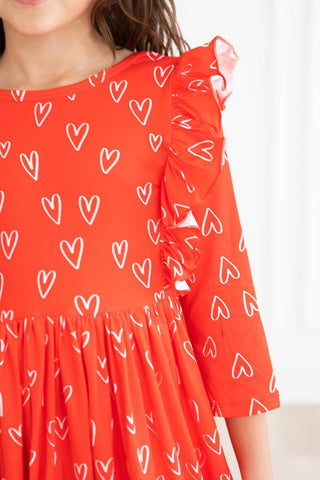 Red dress with white heart patterns worn by a child on a white background