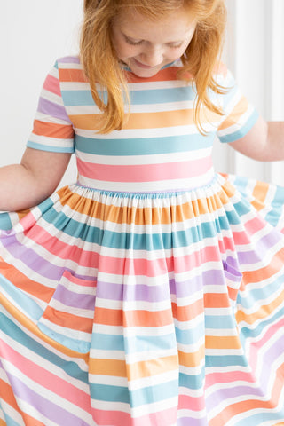 Child wearing a colorful striped dress against a white background