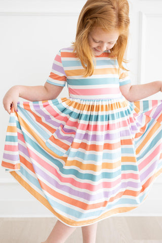 Young girl wearing a colorful striped dress against a white background