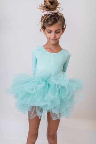 Young girl wearing a light blue ballet leotard with a tutu on a plain background