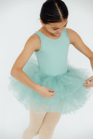 Young girl in a mint green ballet dress on a white background