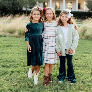 Three young girls standing in front of a house on a grassy lawn.