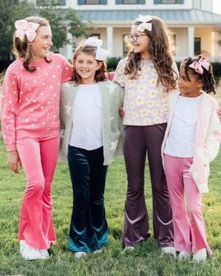 Four young girls standing together outdoors in front of a house