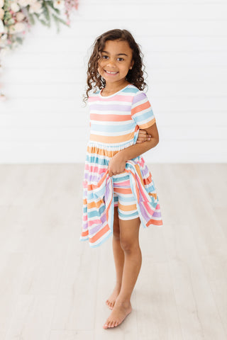 Young girl wearing a colorful striped outfit on a white background