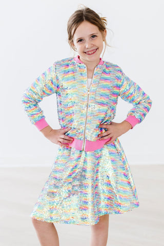 Young girl wearing a colorful skirt with a patterned jacket on a white background