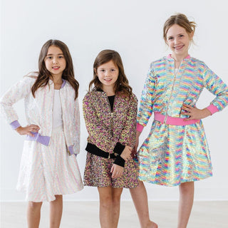 Three young girls wearing colorful dresses on a white background