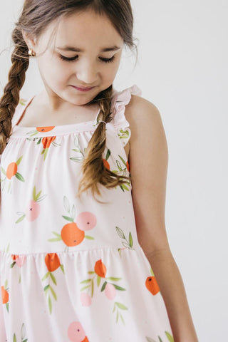 Young girl wearing a fruit print dress with a white background