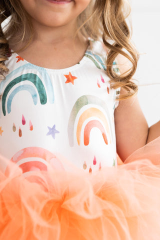 Child wearing a leotard with rainbow and star patterns on a white background