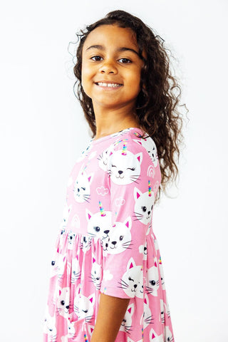 Young girl wearing a pink dress with cat prints on a white background
