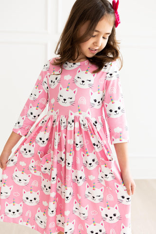 Young girl wearing a pink dress with cat print on a white background