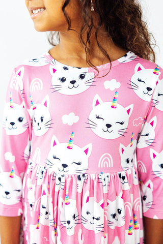 Child wearing a pink dress with cat and unicorn print