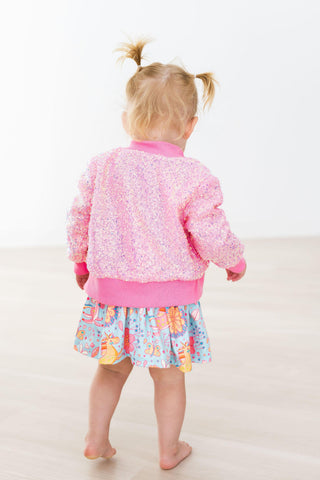 Child wearing a pink jacket and colorful skirt on a white background