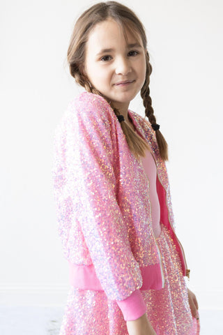 Young girl wearing a pink sequin outfit on a white background