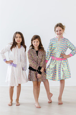 Three young girls wearing colorful dresses on a white background