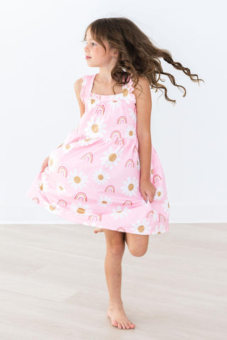 Young girl wearing a pink dress with gold patterns on a white background