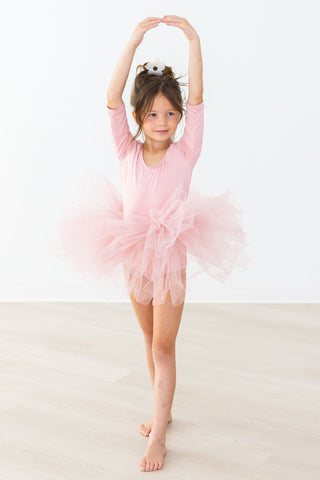 Young girl in a pink ballet outfit posing on a white background