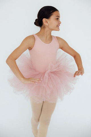 Young girl in a pink ballet outfit with a tutu on a white background