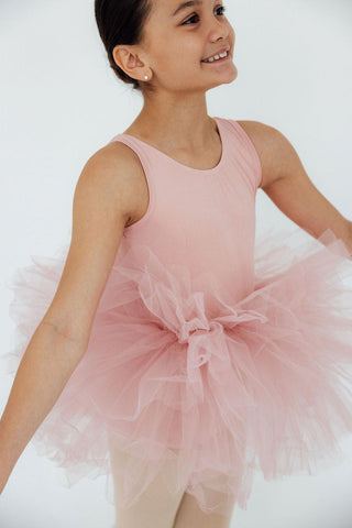 Young girl wearing a pink tutu leotard on a white background