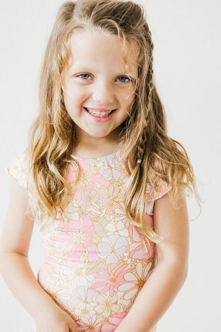 Young girl wearing a floral leotard against a plain background