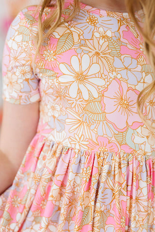 Close-up of a floral dress with pink, orange, and white flowers.