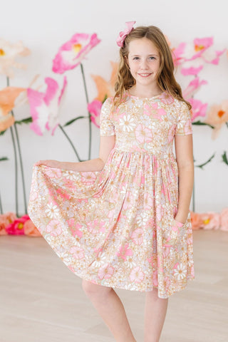 Young girl in a floral dress standing in front of a decorative floral background