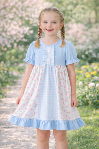 Young girl wearing a light blue dress with floral pattern in an outdoor setting