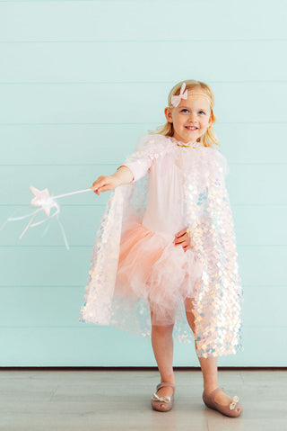 Young girl in a fairy costume holding a wand against a light blue background